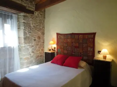 a bedroom with a bed with red pillows and two lamps at Neverending Bierzo in Pobladura de las Regueras