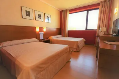 a hotel room with two beds and a television at Hotel MIRAVALLE in Ourense