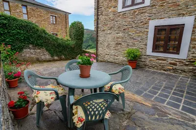 a patio with a table and chairs with flowers at A Casoa II in Santa Eulalia de Oscos