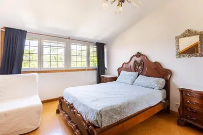 a bedroom with a bed and a chair and windows at Casa Montellos in Betanzos