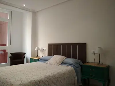 a bedroom with a bed and a chair and a window at Piso Estación Tren Ourense in Ourense