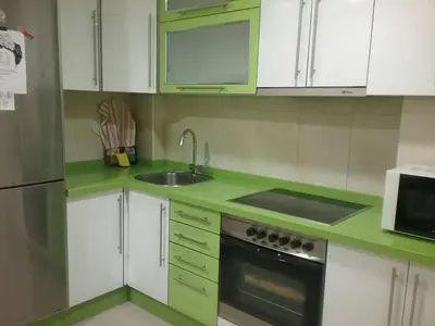 a green kitchen with white cabinets and a sink at Piso Estación Tren Ourense in Ourense