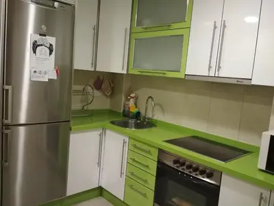 a kitchen with green cabinets and a stainless steel refrigerator at Piso Estación Tren Ourense in Ourense