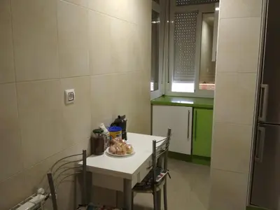a small kitchen with a white table and a refrigerator at Piso Estación Tren Ourense in Ourense