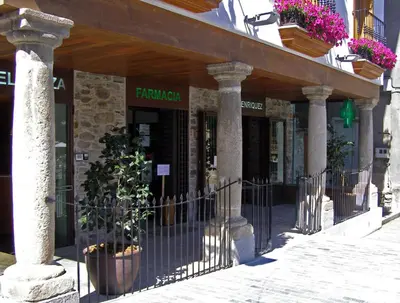 a building with a fence in front of a store at Plaza Mayor in Villafranca del Bierzo