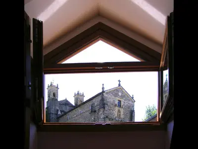 anorthole window in a room with a church in the background at Plaza Mayor in Villafranca del Bierzo