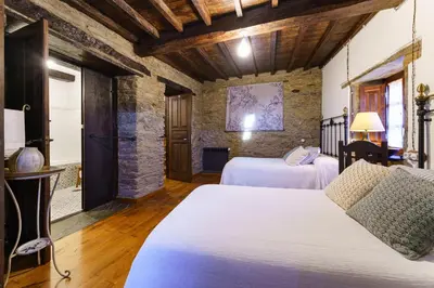 a bedroom with two beds and a stone wall at Casa Brandariz in Santa Maria de Arzua