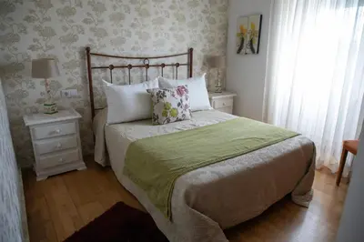 a bedroom with a bed with a green blanket and pillows at Charming house in Teo with balcony and parking included in Rua De Francos