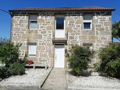 a stone house with a white door and a balcony at Charming house in Teo with balcony and parking included in Rua De Francos