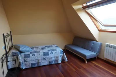 a bedroom with a bed and a couch and a window at Duplex Ribadeo in Ribadeo