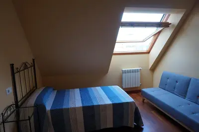 a bedroom with a bed and a blue couch at Duplex Ribadeo in Ribadeo