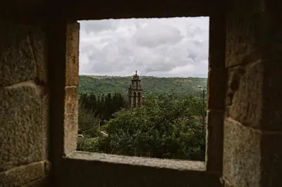 a view of a clock tower through a window at Casa Rural Rectoral de Armariz in Nogueira de Ramuin