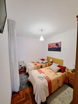 two beds in a room with white walls at Piso Mónica in Ribadavia