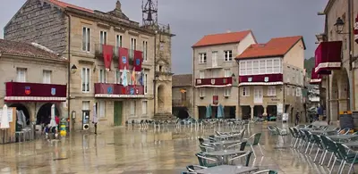 a city street with chairs and buildings in the rain at Piso Mónica in Ribadavia