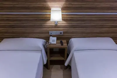 two beds in a room with a phone and a lamp at Hotel Novo Cándido in Ourense