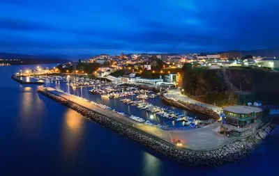 a harbor with boats in the water at night at Escuder Apartamentos Turísticos in Ribadeo