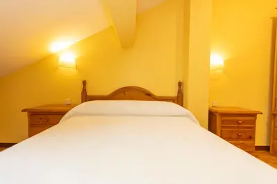 a bedroom with a white bed with two night stands at Escuder Apartamentos Turísticos in Ribadeo