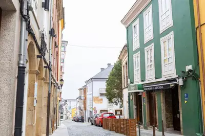 a narrow street with buildings and cars parked on the street at Escuder Apartamentos Turísticos in Ribadeo