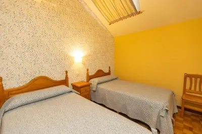 two beds in a room with yellow walls at Escuder Apartamentos Turísticos in Ribadeo