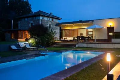 a swimming pool in front of a house at night at Casa Do Bosque in Sarria