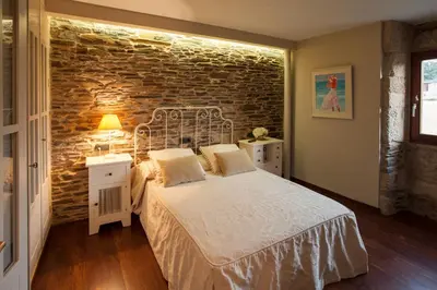 a bedroom with a bed and a brick wall at Casa Do Bosque in Sarria