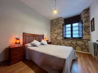 a bedroom with a large bed and a stone wall at El Balcón De Muniellos in Oballo
