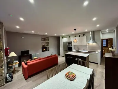 a living room with a red couch and a kitchen at El Balcón De Muniellos in Oballo