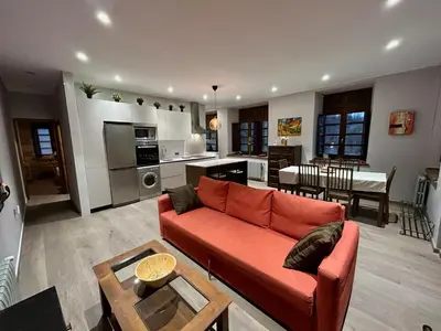 a living room with a red couch and a kitchen at El Balcón De Muniellos in Oballo
