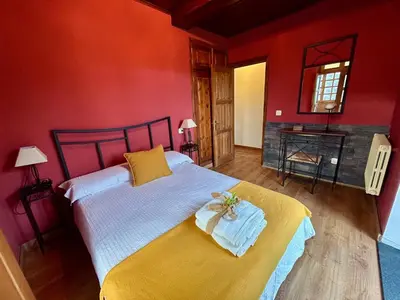 a red bedroom with a bed with a yellow blanket at El Balcón De Muniellos in Oballo