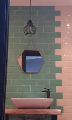 a green wall with a mirror and a bowl on a table at A Casiña de Esther in Teo