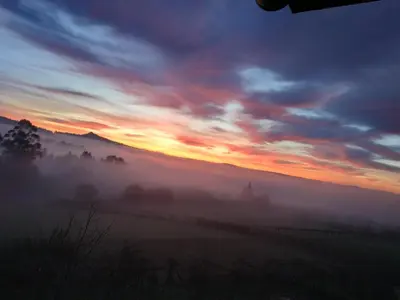 a misty sunrise with a view of a field at A Casiña de Esther in Teo