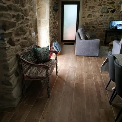 a living room with a chair and a stone wall at A Casiña de Esther in Teo