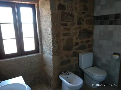 a bathroom with a toilet and a sink and a window at A Casiña de Esther in Teo