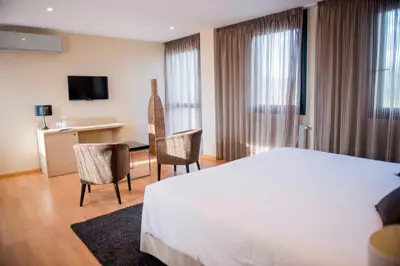 a hotel room with a bed and chairs and a desk at Hotel Meson de Erosa in Herosa