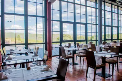a restaurant with tables and chairs and large windows at Hotel Meson de Erosa in Herosa
