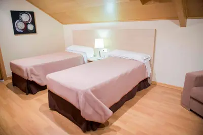 a hotel room with two beds and a couch at Hotel Meson de Erosa in Herosa