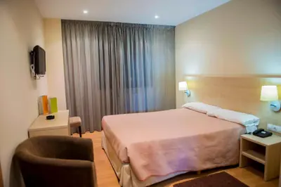 a hotel room with a bed and a chair at Hotel Meson de Erosa in Herosa