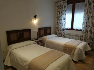a hotel room with two beds and a window at Hotel rural La Campanona in Villager de Laciana