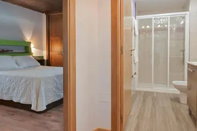 a bedroom with a bed and a bathroom with a toilet at Apartamentos Casa Ramoncín in A Pontenova