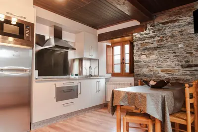 a kitchen with a table and a stone wall at Apartamentos Casa Ramoncín in A Pontenova