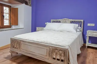 a bed in a room with a purple wall at Apartamentos Casa Ramoncín in A Pontenova