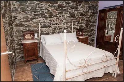 a bedroom with a bed and a stone wall at Apartamentos Casa Ramoncín in A Pontenova