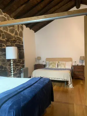 a bedroom with two beds and a stone wall at Casa Grande de Cristosende in Cristosende