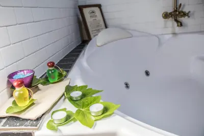 a bathroom with a bath tub with two candles and green leaves at La Moncloa de San Lazaro in Cacabelos