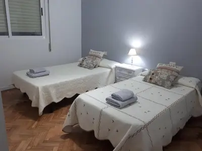 two beds in a room with white walls and wooden floors at Piso Camino de Santiago 2 in Sarria