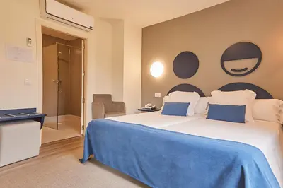 a bedroom with a large bed with a blue blanket at Hotel Boa Vista in Viveiro