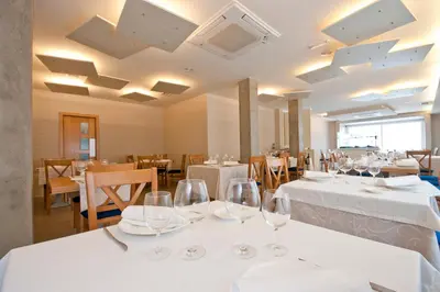 a restaurant with white tables and chairs with wine glasses at Hotel Boa Vista in Viveiro