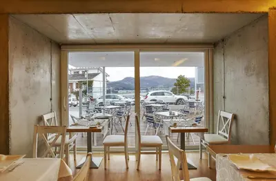 a restaurant with tables and chairs and a view of a parking lot at Hotel Boa Vista in Viveiro