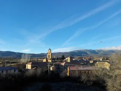 a small town with a church and mountains in the background at La Casa del Filandón- HOTEL RURAL in Quintanilla de Somoza