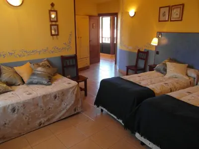 a room with two beds and two chairs in it at La Casa del Filandón- HOTEL RURAL in Quintanilla de Somoza